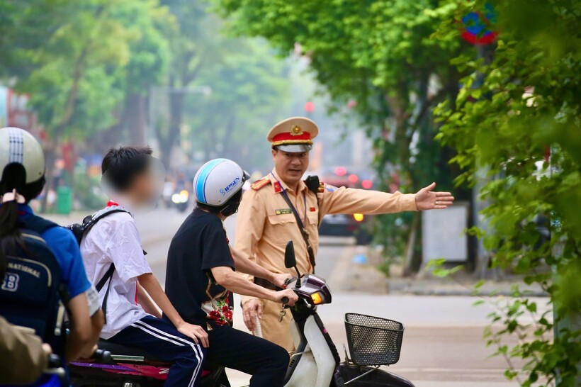 Cảnh sát kiểm tra trường hợp phụ huynh chở học sinh không đội muc bảo hiểm, sáng 6/4.