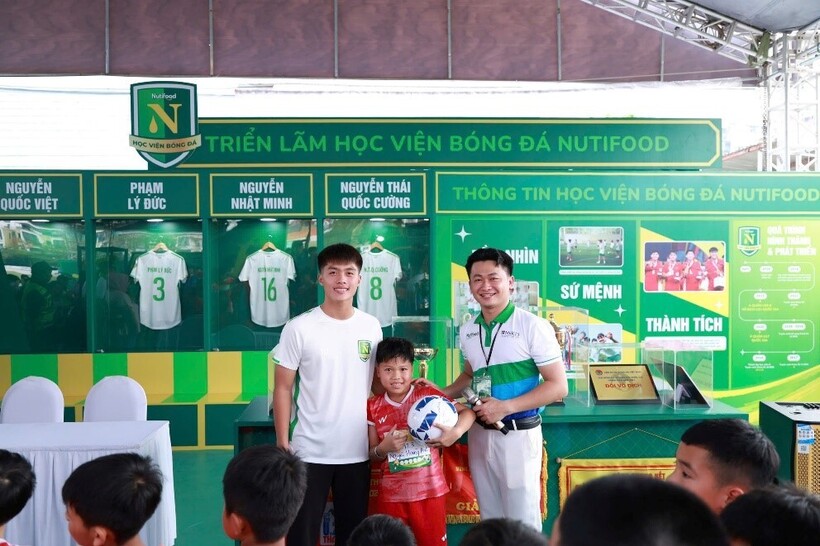 Một cầu thủ nhí hạnh phúc khi được chụp hình với Quốc Việt
