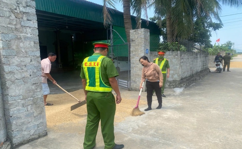 Công an yêu cầu bà Q. gom lúa phơi giữa đường. (Ảnh: VietnamNet)