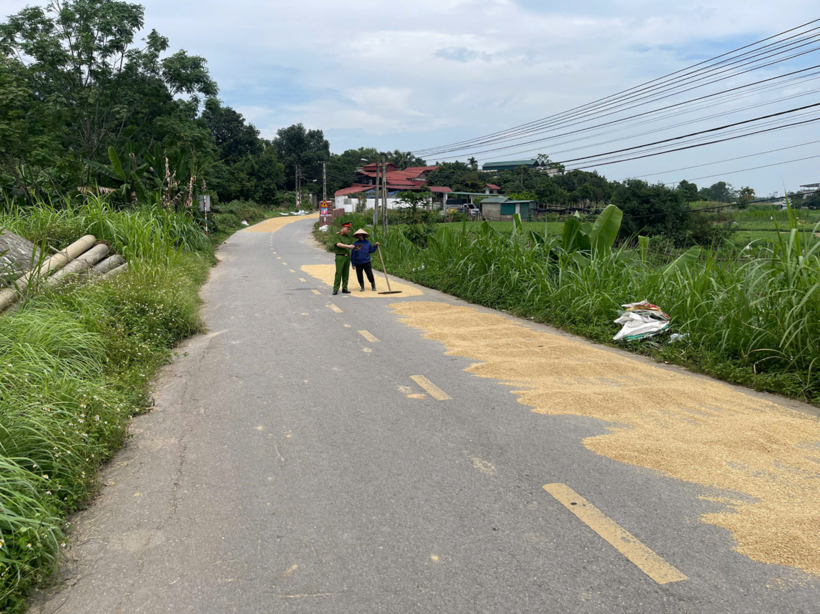 Công an nhắc nhở người dân phơi lúa trên mặt đường. (Ảnh: Công an tỉnh Phú Thọ)