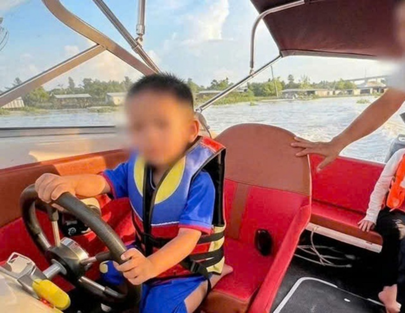 Bé trai 3 tuổi lái ca nô chạy trên sông. Ảnh: Thanh Niên