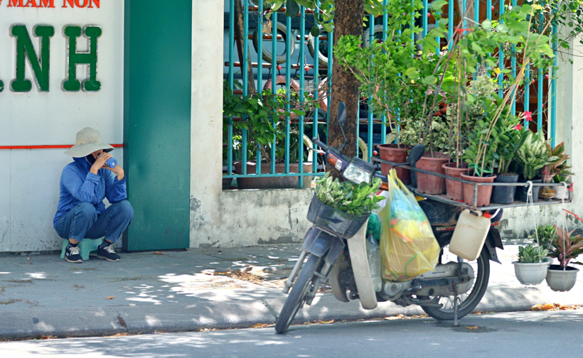 Một người bán hàng phải ngồi lên vỉa hè để nghỉ ngơi