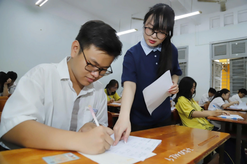 Giám thị hướng dẫn thí sinh ký tên vào đúng ô quy định - Ảnh: NHƯ HÙNG