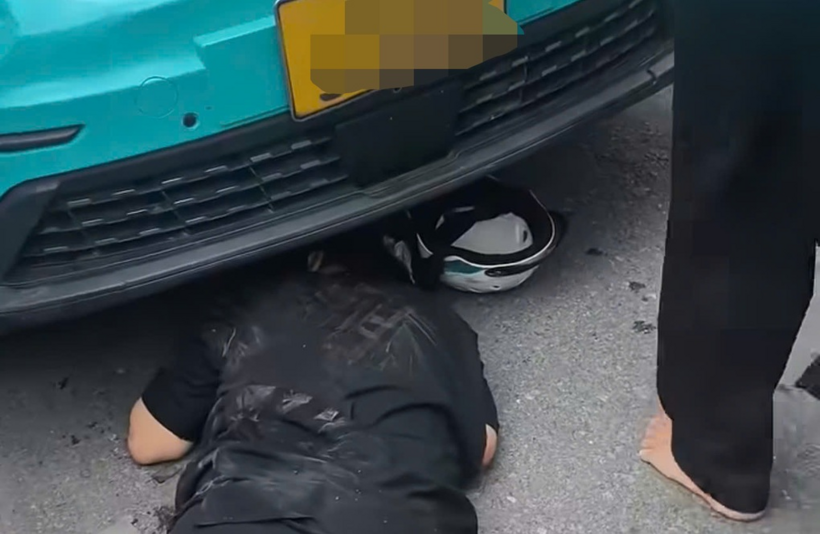 Sau cú va chạm, nữ nạn nhân nằm bất tỉnh phía trước đầu ô tô taxi (Ảnh: Cắt từ clip).