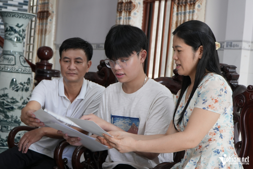 Vinh cùng bố mẹ xem lại thành tích em từng đạt. Ảnh: Hoàng Anh