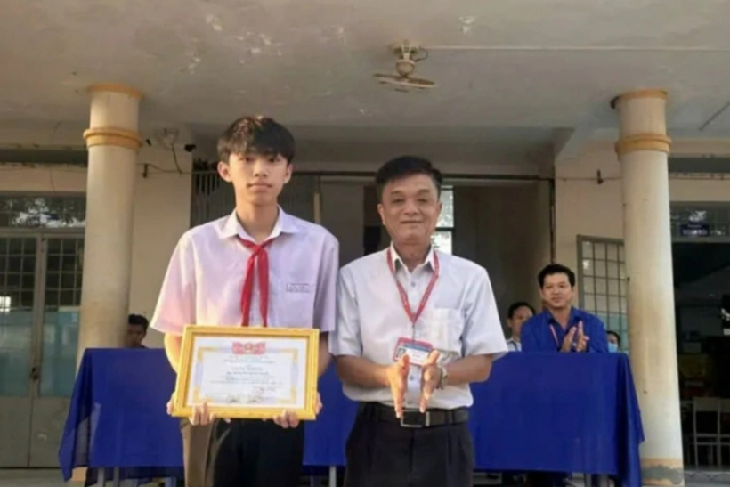 Nguyễn Thiện Nhân (trái) nhận khen thưởng từ thầy hiệu trưởng Trường THCS & THPT Hưng Điền B (Ảnh: NVCC).
