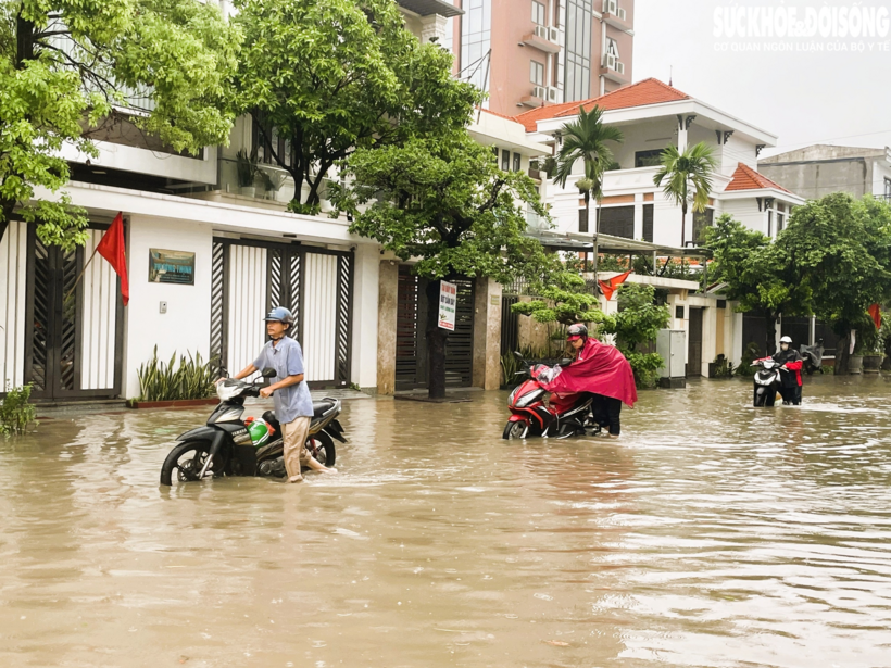 Khu vực gần chợ Lũng lụt sâu, xe chết máy giữa đường khiến người dân phải dắt bộ qua đoạn lụt. Ảnh: T.Dung