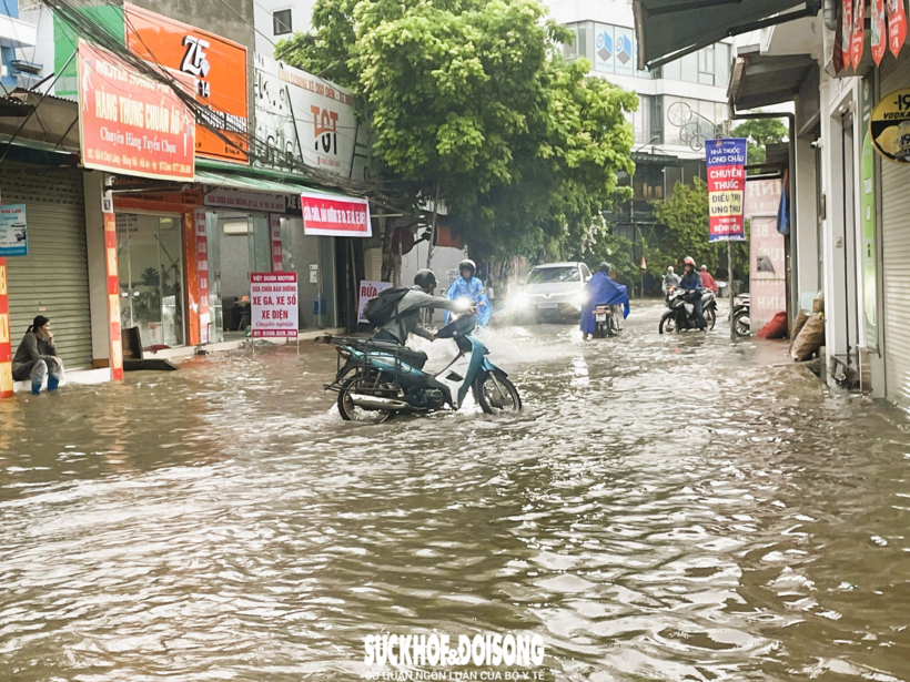 Người dân vật lộn khi di chuyển qua khu vực ngập lụt.