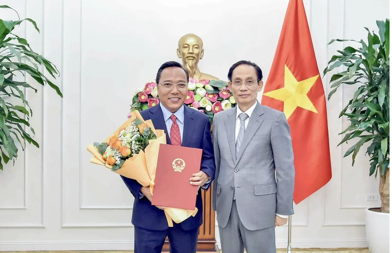 Bộ trưởng Bộ Ngoại giao Lê Hoài Trung trao quyết định của Thủ tướng Chính phủ và tặng hoa chúc mừng ông Nguyễn Hoàng Long được điều động, bổ nhiệm giữ chức Thứ trưởng Bộ Ngoại giao. Ảnh: VGP.