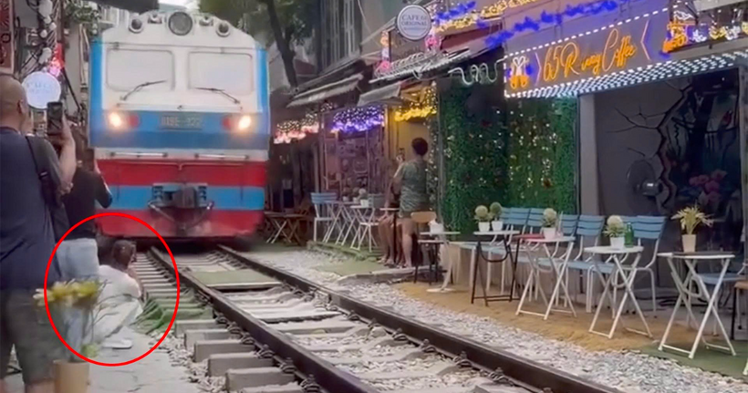 Cô gái ngồi sát đường ray tàu hỏa để ghi hình. (Ảnh cắt clip)