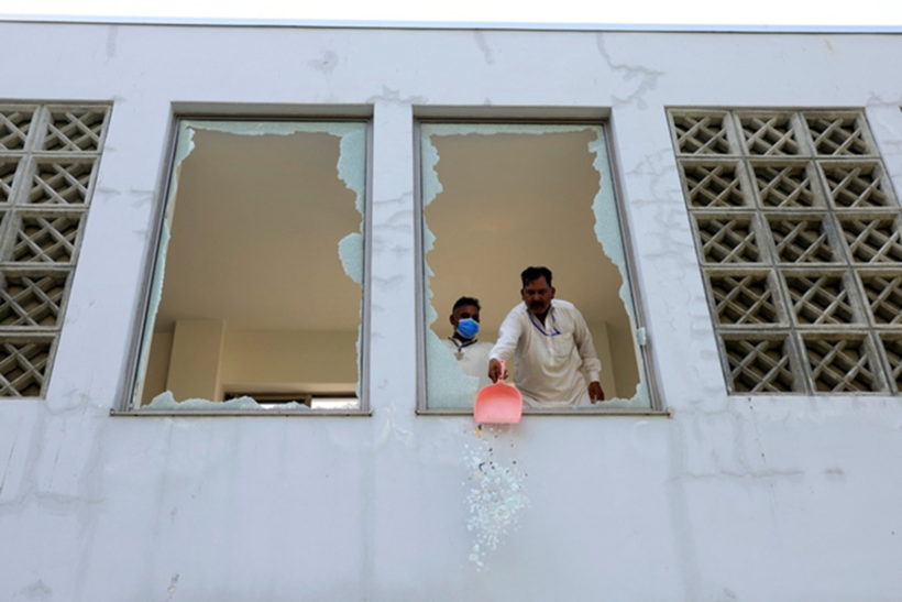Nhân viên dọn dẹp cửa sổ kính bị vỡ sau vụ cháy bệnh viện ở Islamabad ngày 26/8. Ảnh: Reuters