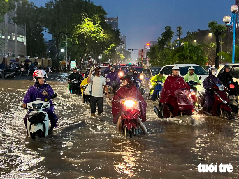 Người Hà Nội bì bõm trong biển nước tại đường Hoàng Quốc Việt - Ảnh: PHẠM TUẤN