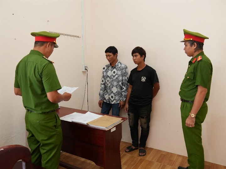 Cơ quan điều tra tống đạt các quyết định khởi tố Lê Văn Khanh và Lê Văn Nhàn (áo đen). Ảnh: Công an Cần Thơ