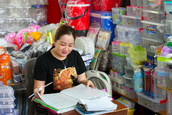Tiểu thương quầy Diêm Thuận, chuyên mua bán các mặt hàng nhựa và melamine tại chợ Bình Tây (TP.HCM), kiểm tra sổ sách và tính toán hóa đơn - Ảnh: HỮU HẠNH/ Theo báo Tuổi trẻ.