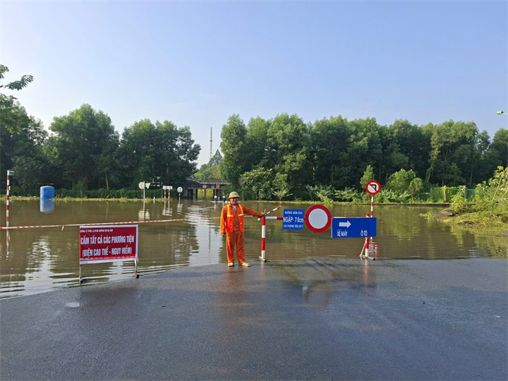 Lực lượng chức năng phân luồng qua đoạn ngập úng trên Đại lộ Thăng Long. Ảnh: Hà Nội Mới