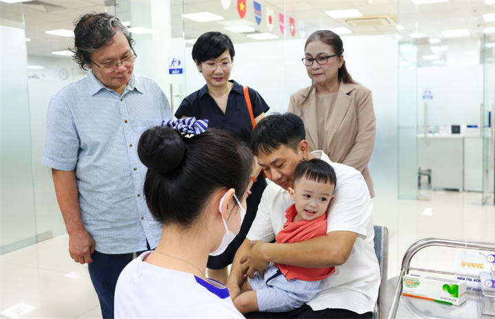 Bác sĩ Trương Hữu Khanh, người có hàng chục năm gắn bó với công tác điều trị các ca tay chân miệng nặng tại Việt Nam chứng kiến em bé đầu tiên tại Việt Nam được tiêm vắc xin phòng EV71 tại VNVC. Ảnh: Nhân Lê