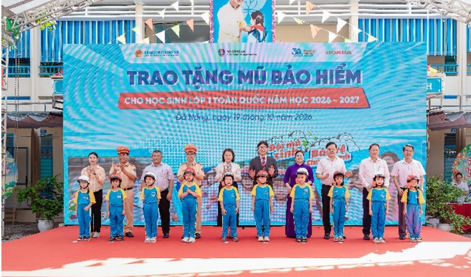Các đại biểu trao tặng mũ bảo hiểm cho các em học sinh lớp Một trường Tiểu học Ngô Mây (Ảnh: HVN).