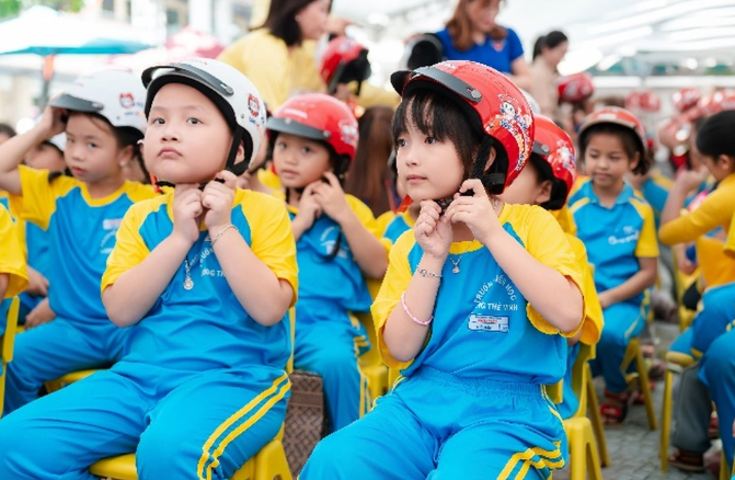 Các em học sinh trường Tiểu học Ngô Mây thực hành đội mũ bảo hiểm đúng cách và an toàn (Ảnh: HVN).